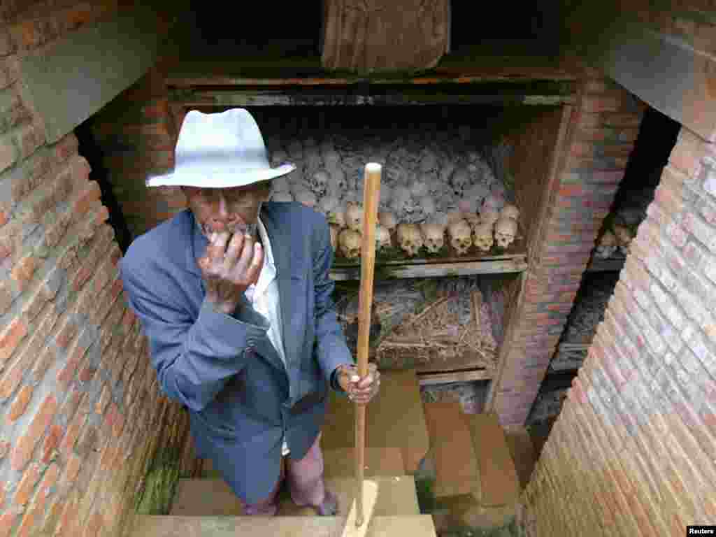 A Rwandan worker wipes as he cleans a mass grave outside the church in Nyanza, Rwanda April 4, 2004. Vowing never again, Rwandans began a week of commemoration on Sunday for the estimated 800,000 people killed a decade ago in 100 days of genocide that the outside world did little to prevent. REUTERS/Radu Sigheti 