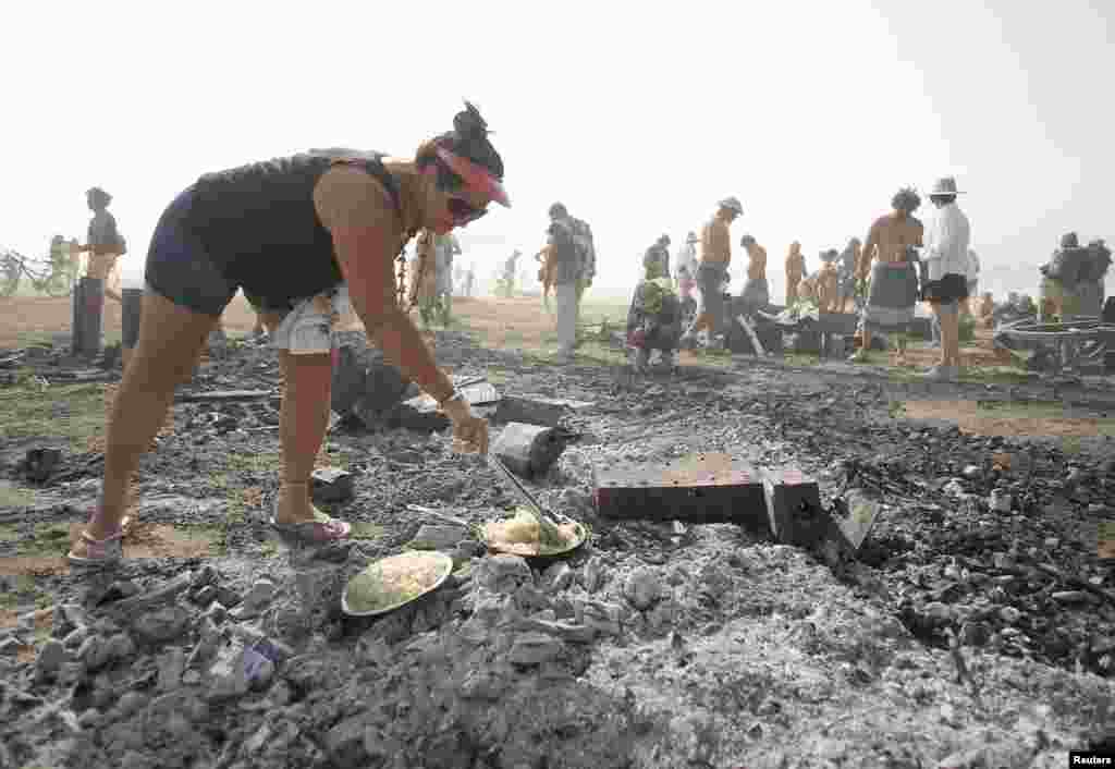 Rhonda Clark cooks breakfast on the burned remains of the "man" during the Burning Man 2013 arts and music festival in the Black Rock Desert of Nevada.