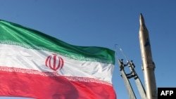 The Iranian national flag flutters next to one of the country's surface-to-surface missiles. (file photo)