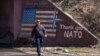Një burrë duke ecur mbrapa mbishkrimit “Faleminderit NATO” dhe "Faleminderit SHBA", si dhe flamurit amerikan në Stagovë, vendbanim në Kaçanik, Kosovë.