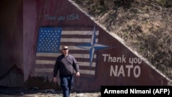 Muškarac prolazi pored grafita sa natpisom "Hvala NATO" i zastavom SAD-a u blizini sela Stagovo, Kosovo, mart 2019.