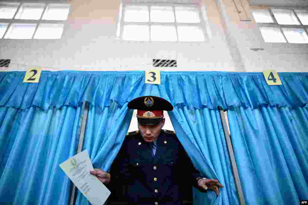 A Kazakh policeman votes during parliamentary elections in the Kazakh city of Baikonur on March 20. (AFP/Kirill Kudryavtsev)