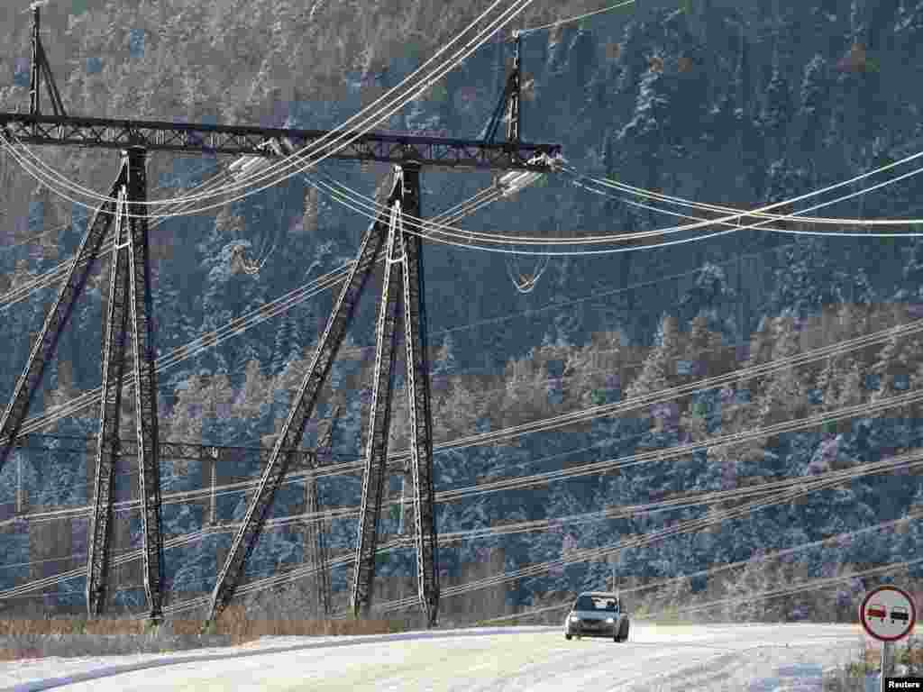 A car drives under high-voltage power lines from Krasnoyarsk hydroelectric power station, some 48 kilometers south of the Siberian city of Krasnoyarsk, on November 11. Photo by Ilya Naymushin for Reuters