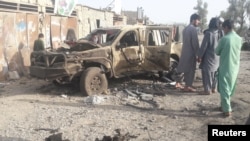 Жители на градот Фарах покрај оштетено возило по нападите. 