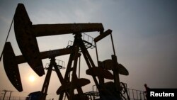  Un muncitor inspectează o pompă de extragere a petrolului din câmpul petrolier PetroChina, din Panjin