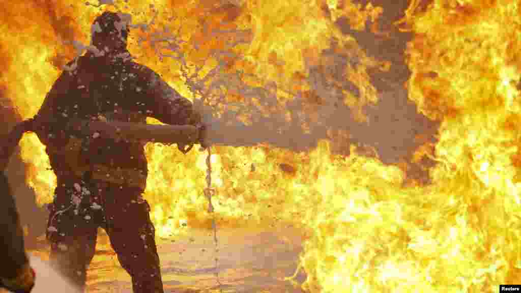 An Afghan firefighter sprays foam on a burning fuel tanker in Kabul on April 23. (Reuters/Omar Sobhani)