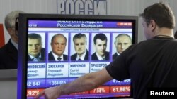 Russia -- A man gestures near a screen, which shows the preliminary results of the presidential elections, at the Central Election Commission headquarters in Moscow, 04Mar2012