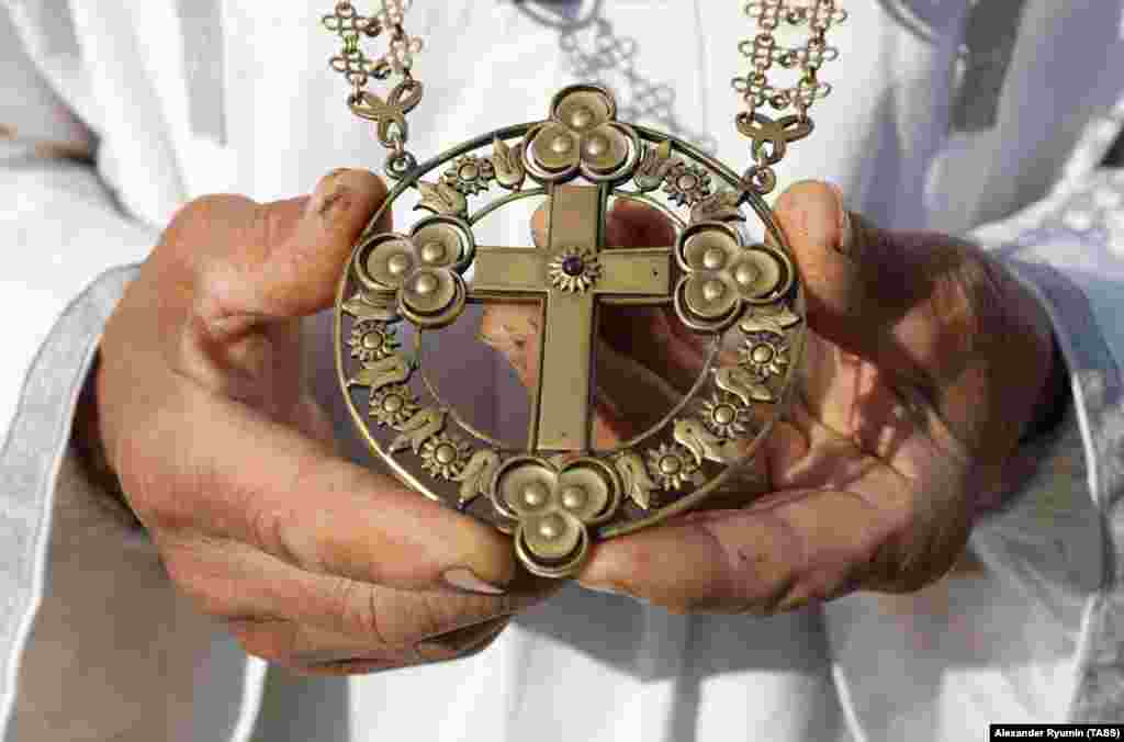 A Vissarionite holds a cross with three circles on each tip. In a 2012 documentary, one follower described seeing a triangular UFO in the sky above the religious settlement with "three spheres" in each corner. 