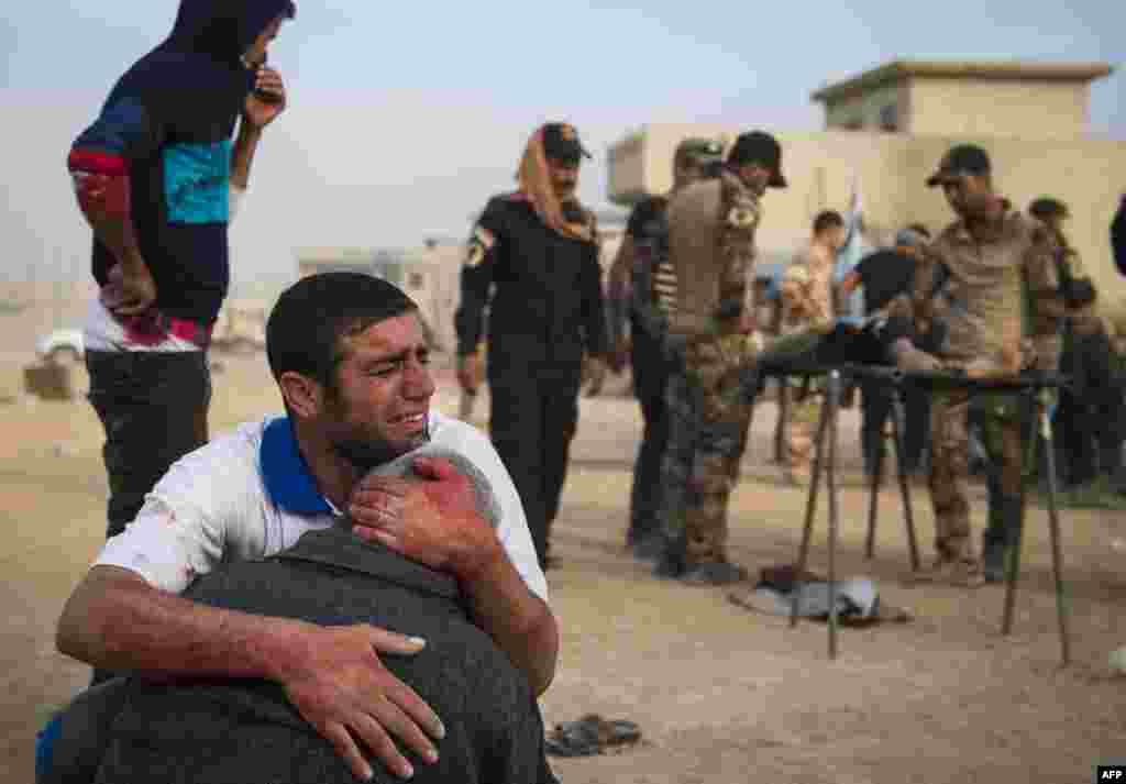 The father and grandfather of 15-year-old Shafiq mourn as Iraqi forces surround his body at an outdoor field clinic in the Samah neighborhood in Mosul, Iraq, on November 13. (AFP/Odd Andersen)