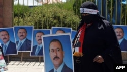 A Yemeni woman walks past portraits of Yemeni President Ali Abdullah Saleh during a pro-regime rally after the Friday noon prayer in Sanaa on October 21.