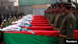 Afghan honor guards stand next to coffins as they pay tribute to soldiers who were killed in an Taliban attack in Kunar province.