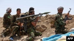 Iraqi Shi'ite fighters man a post as they fire towards Islamic State (IS) group positions in Anbar Province on May 19, 2015.