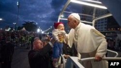 Папа римский Франциск благословляет малыша, которого держит на руках верующий отец. Рио-де-Жанейро, 26 июля 2013 года.