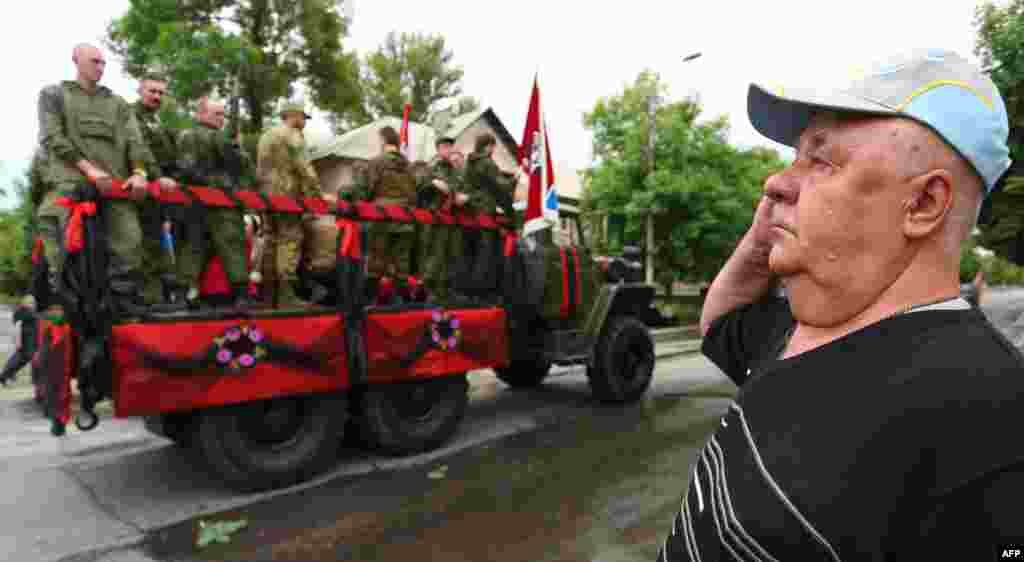 A man salutes as a truck with the coffin of Ukrainian rebel leader Alexey Mozgovoi passes along a street during his funeral ceremony in the town of Alchevsk, some 40 kilometers from Luhansk in eastern Ukraine. (AFP/Aleksey Filippov)