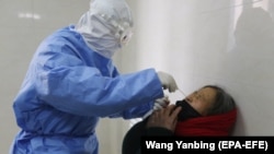 Doktor uzima bris za testiranje SARS-CoV-2 ženi u bolnici u okrugu Yinan, u istočnoj provinciji Shandong, 12. februar 2020.