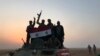 Syrian forces gestures as they carry the national flag in the village of Suway'iah, near the Syrian border town of Albu Kamal, on November 9, 2017. File photo