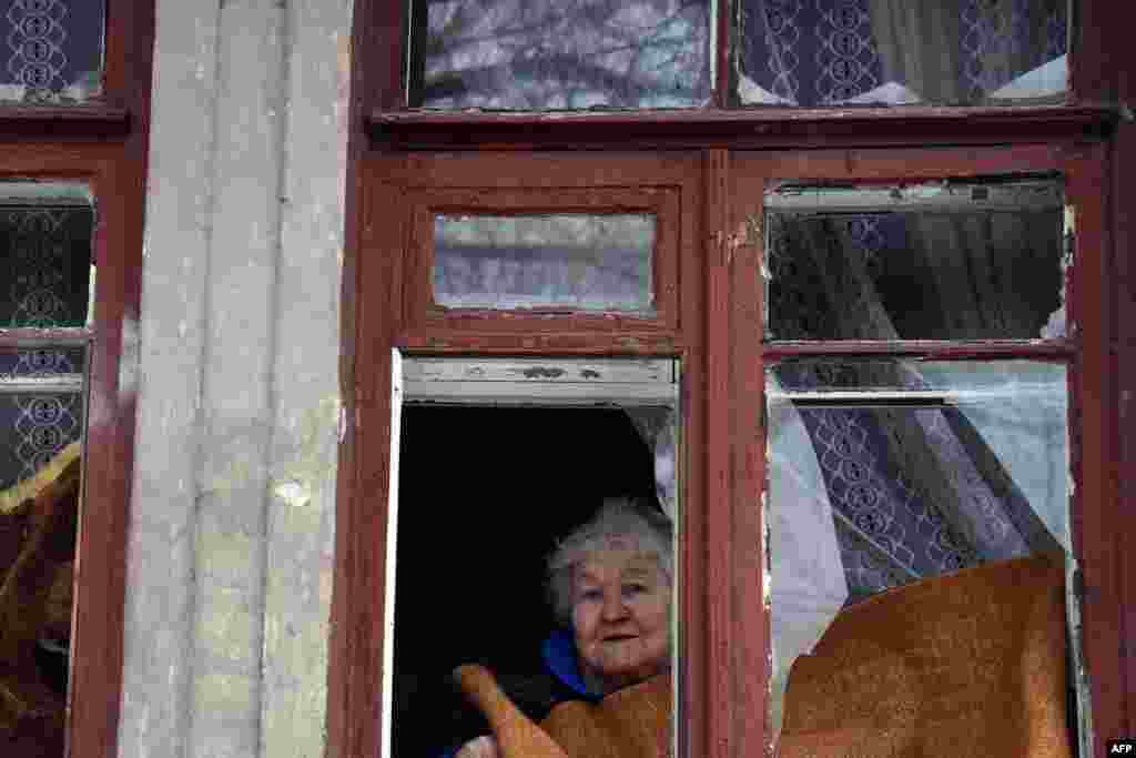 An elderly woman looks on after a shell hit a residential area in Donetsk&#39;s Kyibishevsky district.