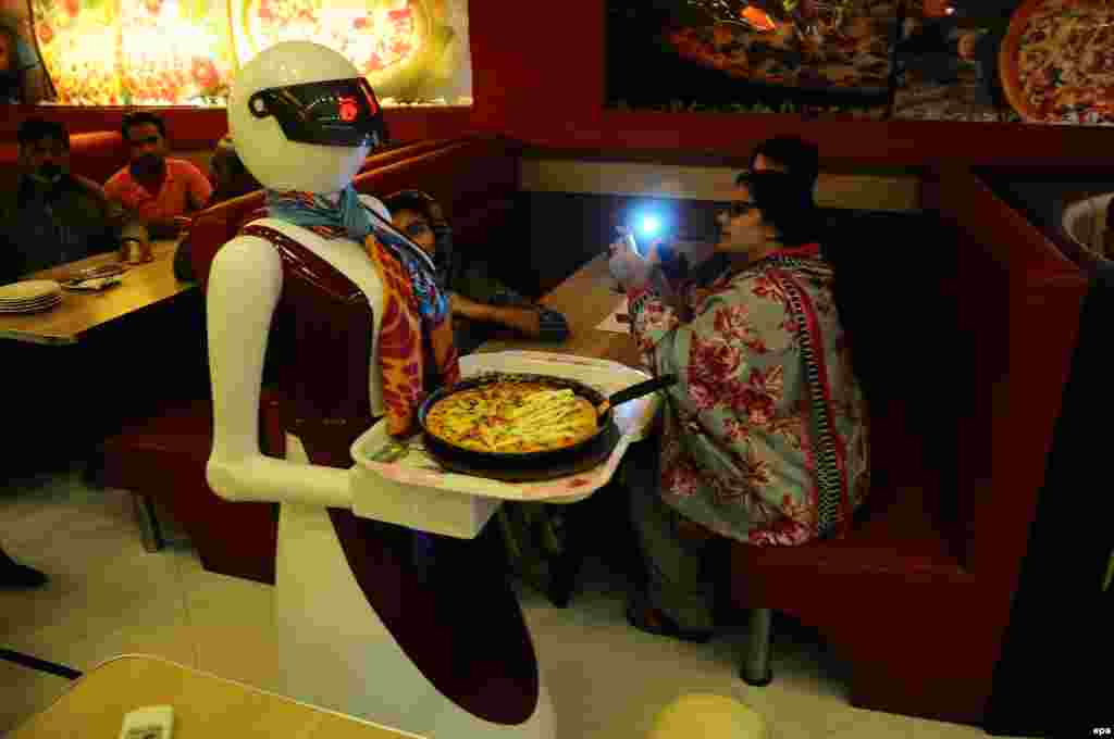 A robot waiter serves pizza to customers at the Pizza.com restaurant in Multan, Pakistan. Syed Usama Aziz, an electrical engineering student, created the robot waiter for his father's business. According to reports, it took Aziz about eight months and $3,800 to build the robot. (epa/Faisal Kareem)