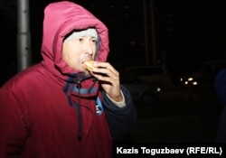 Участник акции протеста ест пирожок, которые на площади раздавала сочувствующая забастовщикам жительница города. Актау, 20 декабря 2011 года.