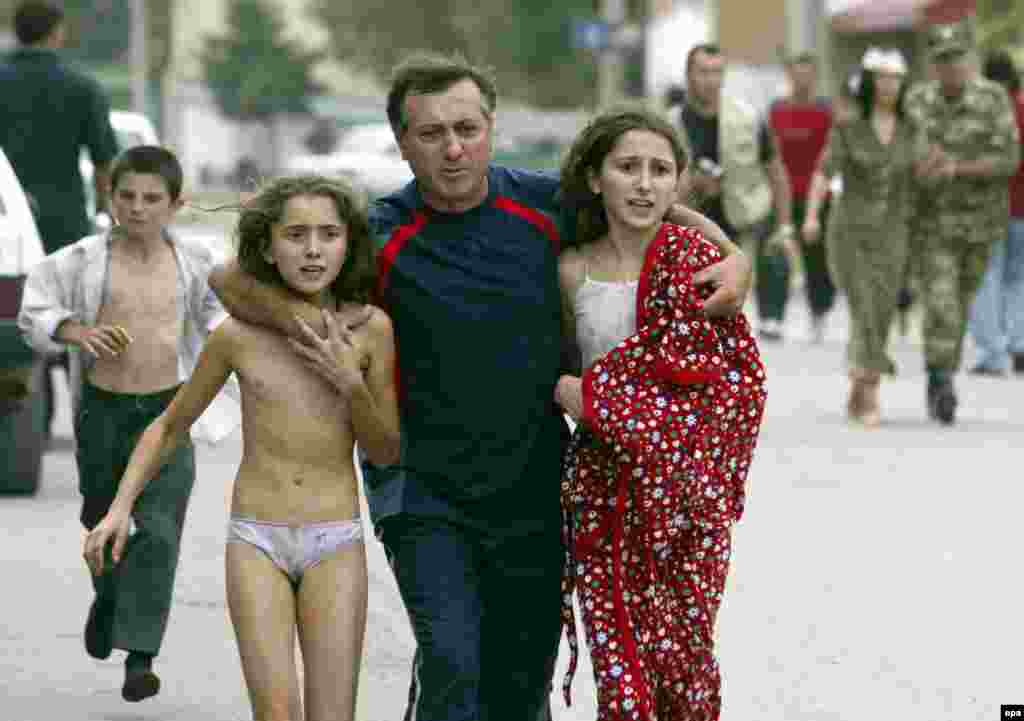 A man assists two young hostages who managed to escape from the school after special forces stormed the building.