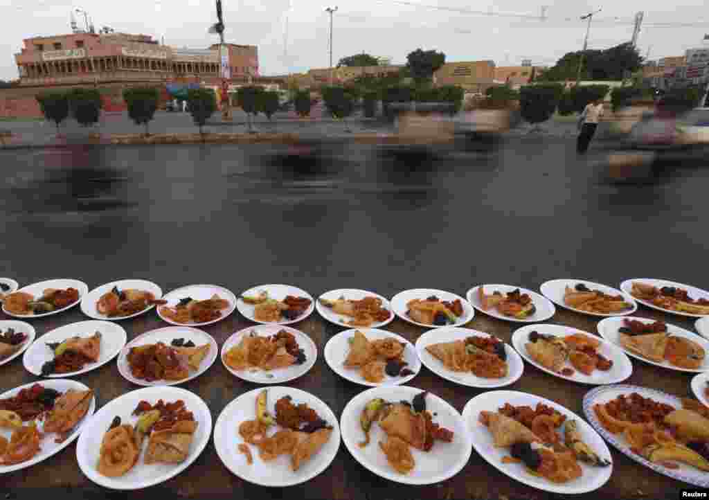 Commuters pass plates of food, placed for passersby to break their fast during the holy fasting month of Ramadan, along a road in Karachi, Pakistan, on July 1. (Reuters/Akhtar Soomro)