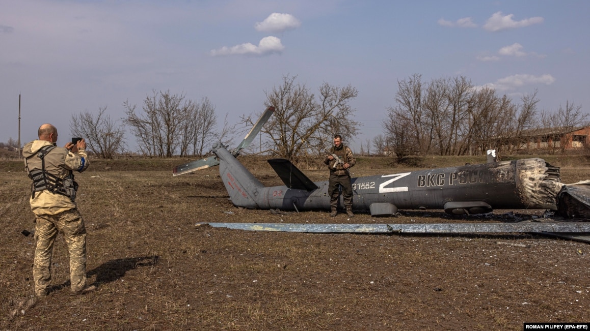Український військовослужбовець позує для фотографії біля знищеного російського гелікоптера з літерою Z, символом російського вторгнення до України, у відбитому українською армією селі Мала Рогань, що поблизу Харкова, 31 березня 2022 року