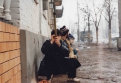 Residents take cover while using a homemade periscope to check for danger on Lenin Avenue