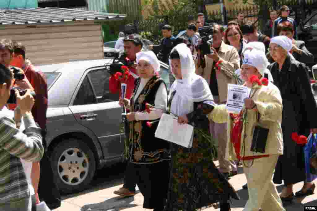 Женщины в белых платках пытаются совершить шествие, чтобы возложить цветы к Монументу Независимости. Посередине - поэтесса Айсулу Кадырбаева. Алматы, 1 мая 2010 года. 