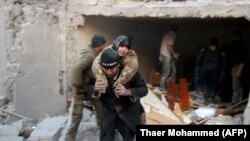 A Syrian rescuer carries a woman who was saved from the rubble of a building following reported air strikes on Aleppo's rebel-held district of Al-Hamra on November 20. 