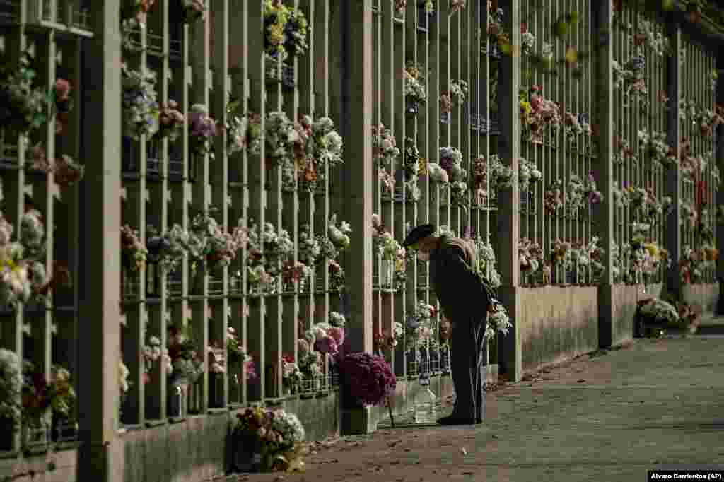 A man stands in front of tombs decorated with flowers in Pamplona, northern Spain.