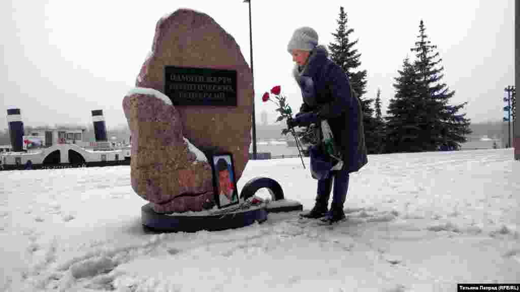 Женщина возлагает цветы к памятнику жертв политических репрессий в Красноярске.