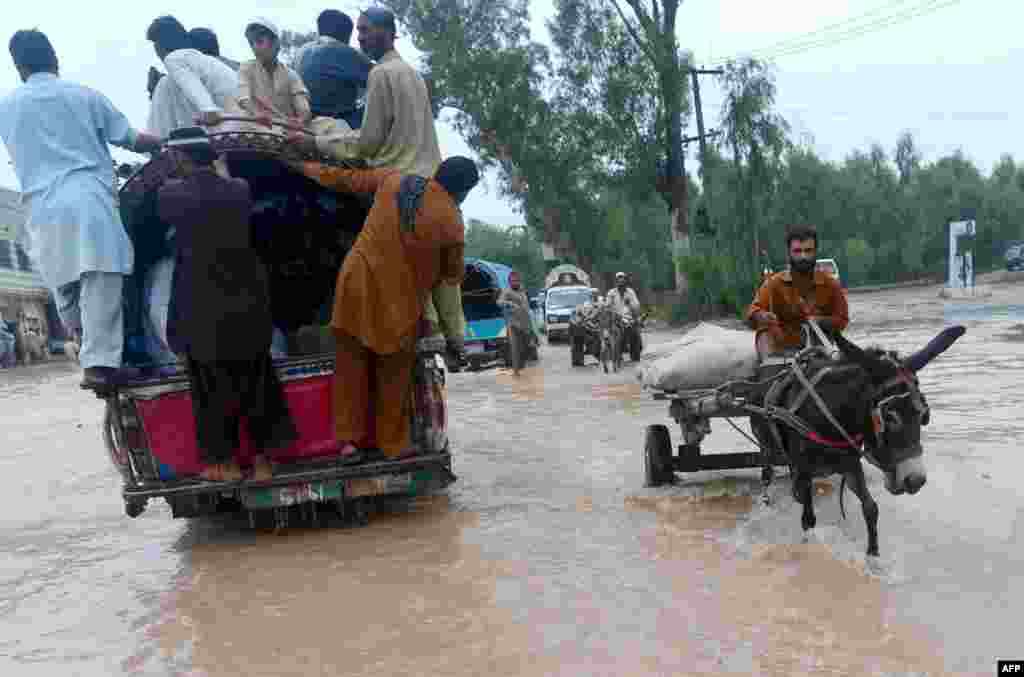 Pakistanis cross a flooded street in Peshawar.
