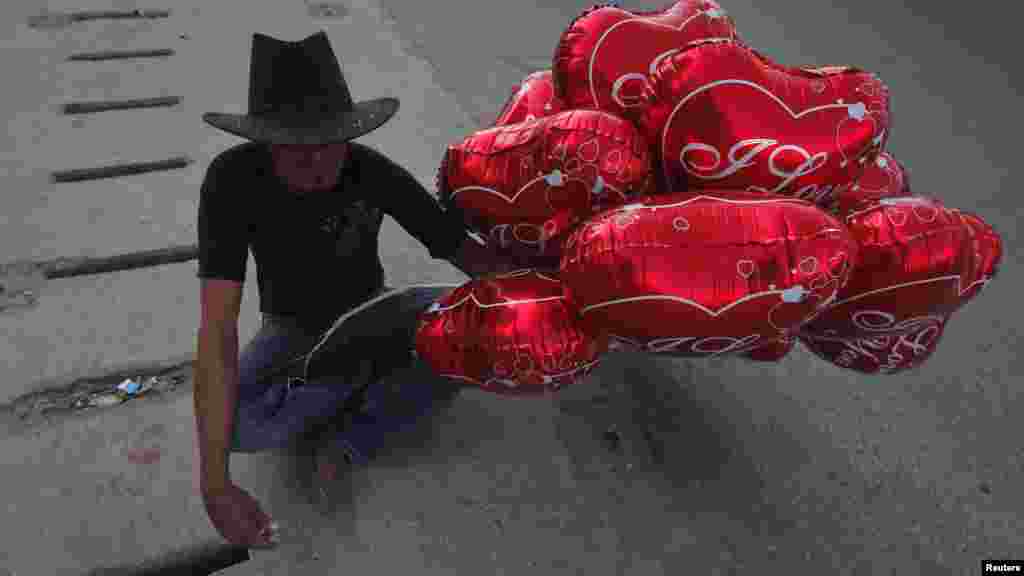 A man holds Valentine's Day balloons for sale while waiting for customers along the roadside in Karachi, Pakistan. (Reuters/Akhtar Soomro)