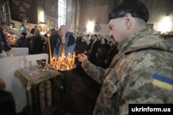 Український військовослужбовець ставить свічку під час Різдвяного богослужіння в соборі святого Івана Богослова. Харків, 7 січня 2016 року