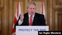 Премиерът на Великобритания Борис Джонсън дава пресконференция. Надписът гласи: "Пазете Националната здравна служба"