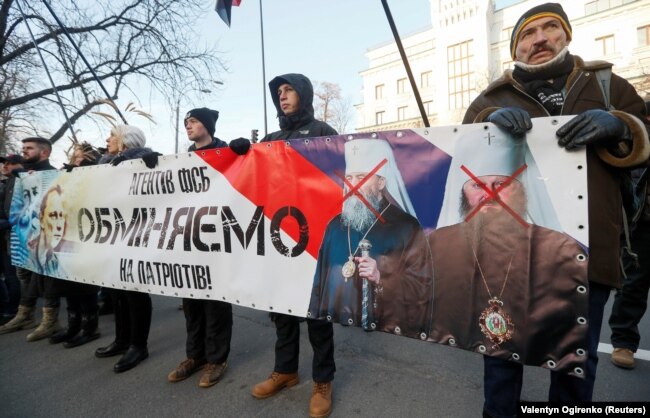 Активісти з банером «Агентів ФСБ обміняємо на українських патріотів!», на якому зображені, з одного боку, глава УПЦ (МП) Онуфрій і намісник Києво-Печерської лаври Павло, а з іншого боку – Микола Карпюк і Станіслав Клих, які ув’язнені в Росії. Київ, 24 листопада 2018 року
