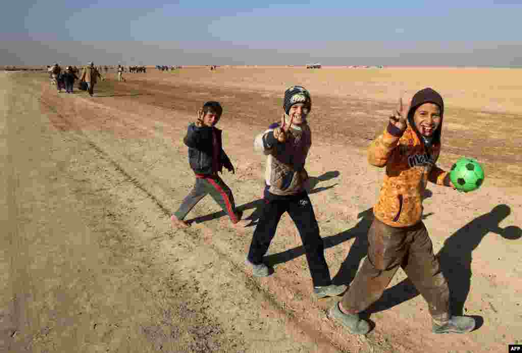 Iraqi boys, who fled their homes west of Mosul due to the fighting between government forces and Islamic State jihadists, gesture as they are escorted from a makeshift camp to safer areas by Shi'ite paramilitary forces. (AFP/Ahmad Al-Rubaye)