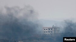 A black flag belonging to the Islamic State is seen through the smoke on top of a house in the Syrian town of Kobani on October 17.