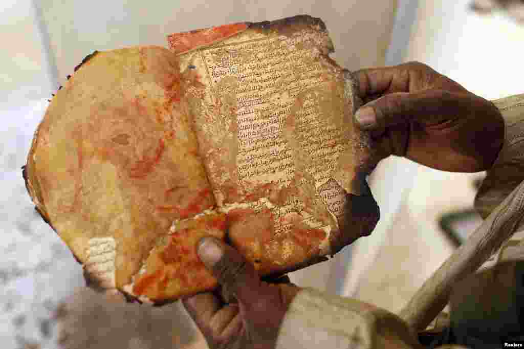 A museum guard displays a burned ancient manuscript at the Ahmed Baba Center for Documentation and Research in Timbuktu, Mali. The majority of Timbuktu&#39;s ancient manuscripts appear to be safe and undamaged after the Saharan city&#39;s 10-month occupation by Islamist rebel fighters. (Reuters/Benoit Tessier)