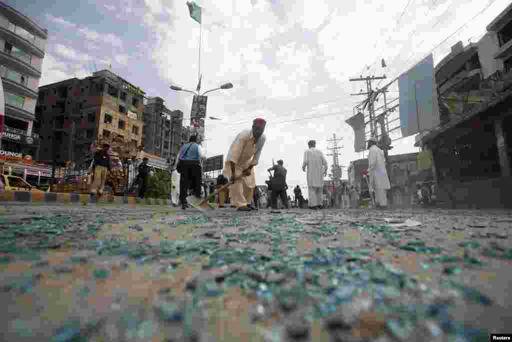 Rescue workers collect shattered glass from the site of a bomb blast on University Road in Peshawar, Pakistan, which killed eight people on April 29. (Reuters/Ammar Abdullah)