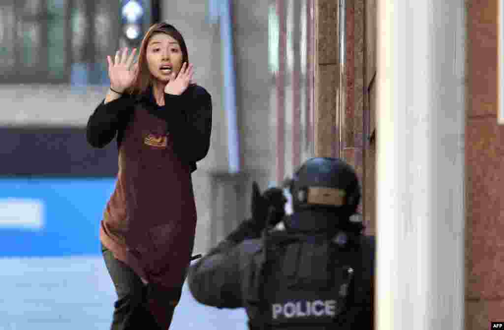 One of the hostages runs toward police from a cafe in the central business district of Sydney during a daylong hostage incident in which two hostages and the Iranian-born gunman were killed. (AFP/Saeed Khan)