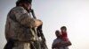 U.S. soldiers speak with an Iraqi man and child about security in the area while out on patrol in July.