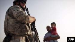 U.S. soldiers speak with an Iraqi man and child about security in the area while out on patrol in July.