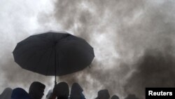 Serbia -- Migrants protect themselves from the rain as they wait to cross the border with Croatia near the village of Berkasovo, October 19, 2015