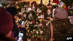 Цветы и свечи возле портрета короля Михая I у Королевского дворца в Бухаресте