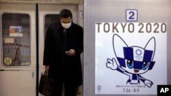 Організатори Олімпіади-2020 спростовують чутки, що Ігри влітку можуть скасувати чи перенести через поширення коронавірусу (на фото: чоловік у масці виходить з вагона поїзда, на якому зображений олімпійський логотип, 31 січня 2020 року, Токіо, Японія)