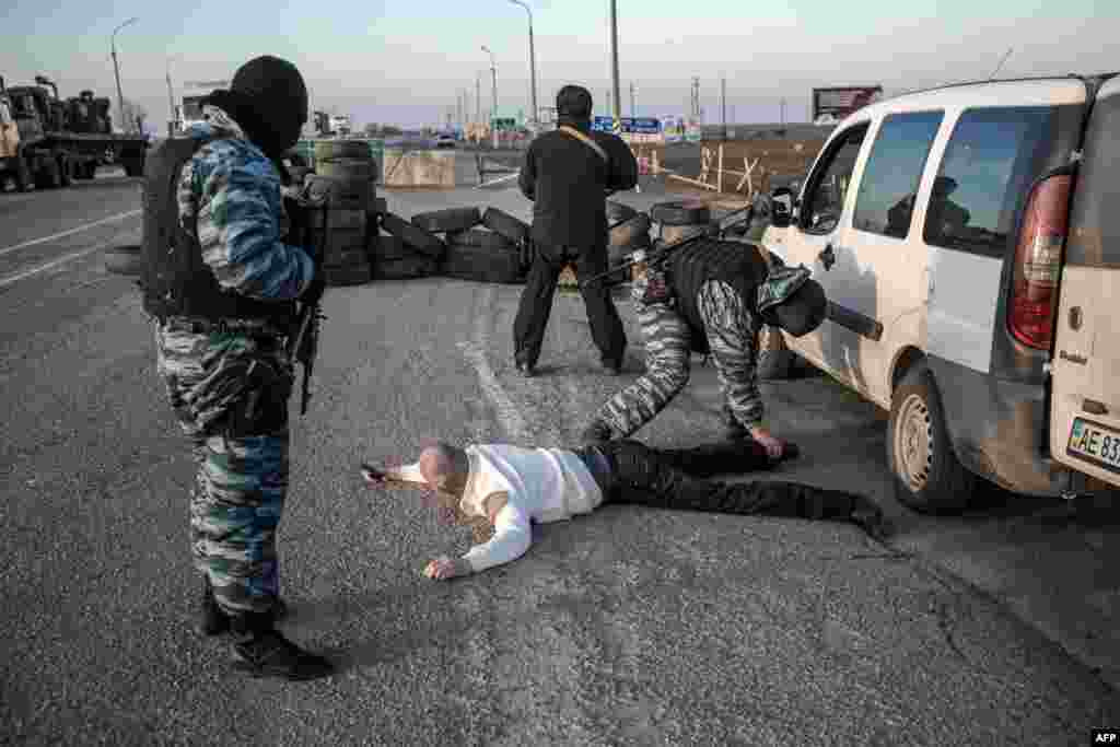 Людину обшукують проросійські сепаратисти на виставленому ними ж кордоні між материковою Україною та півостровом неподалік від Чонгара, 10 березня 2014 року