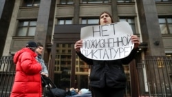 A protester holds a poster reading, "No lifelong dictatorship" while standing in a one-man picket at the State Duma in Moscow on March 13.