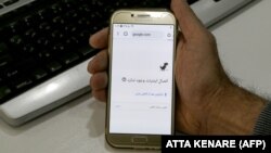 A man holds a smartphone connected to a WiFi network without Internet access at an office in Tehran on November 17.