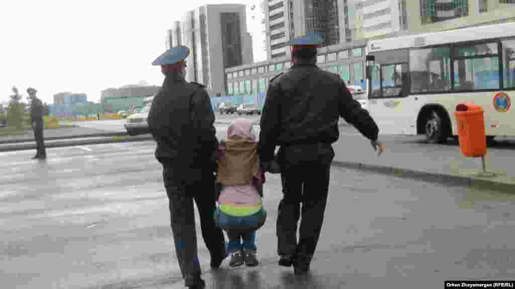 Полицейские задержали убегавшую девушку и несут ее в автобус. Астана, 22 мая 2013 года.